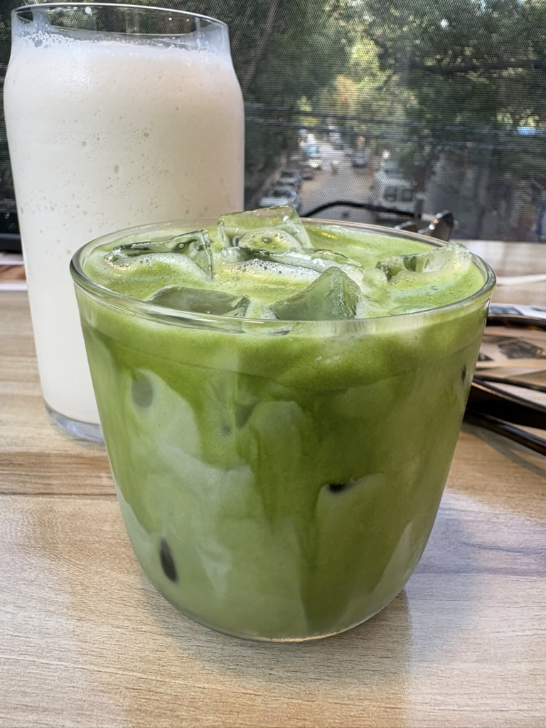 Iced matcha latte in a glass on a café table by the window
